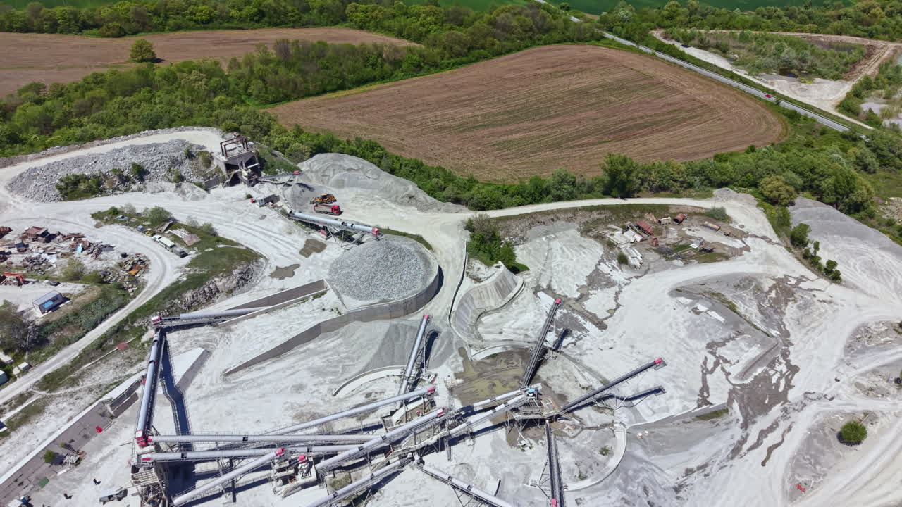Worksite shows the equipment and machinery used in quarrying along with the landscape of the surrounding area and the different stages of extraction in action