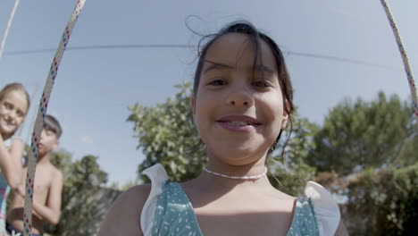 happy girl taking selfie while swinging at backyard playground.