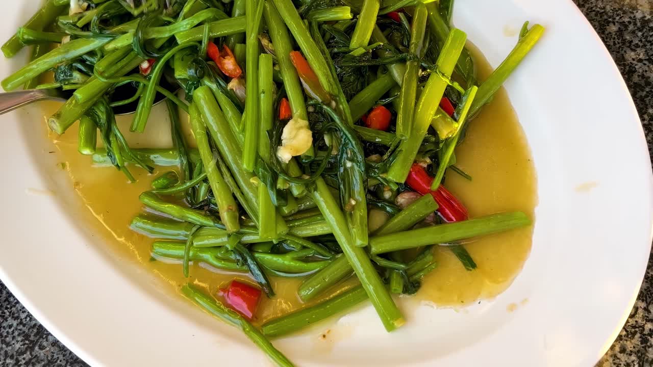 A colorful dish of stir-fried greens with red chili and garlic in a savory sauce.