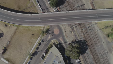 Static-aerial-perspective-of-a-silver-vehicle-entering-and-exiting-round-about-on-summers-day