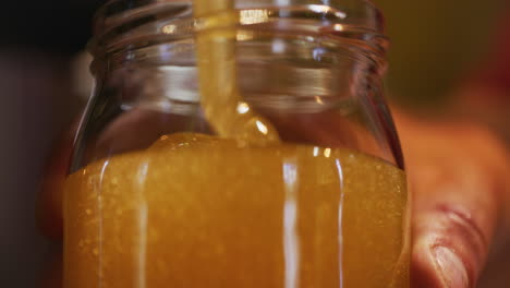 close-up of pouring fresh organic honey into jar