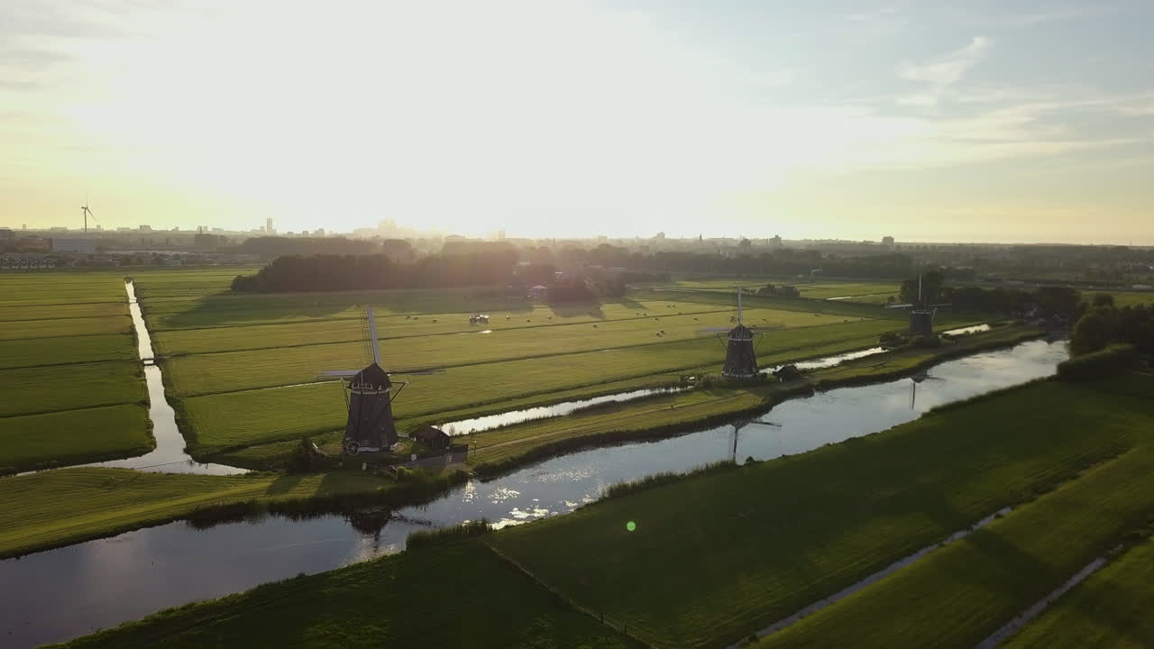 Aerial shot of three iconic windwills in Wilsveen, the Netherlands, flyign towards them during golden hour over green fields