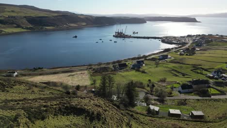 Flying-past-male-observer-towards-Highland-fishing-port-at-Idrigil-Bay-Uig-Isle-of-Skye-Scotland