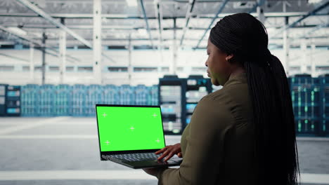 technician in data center uses green screen laptop to deploy server architecture
