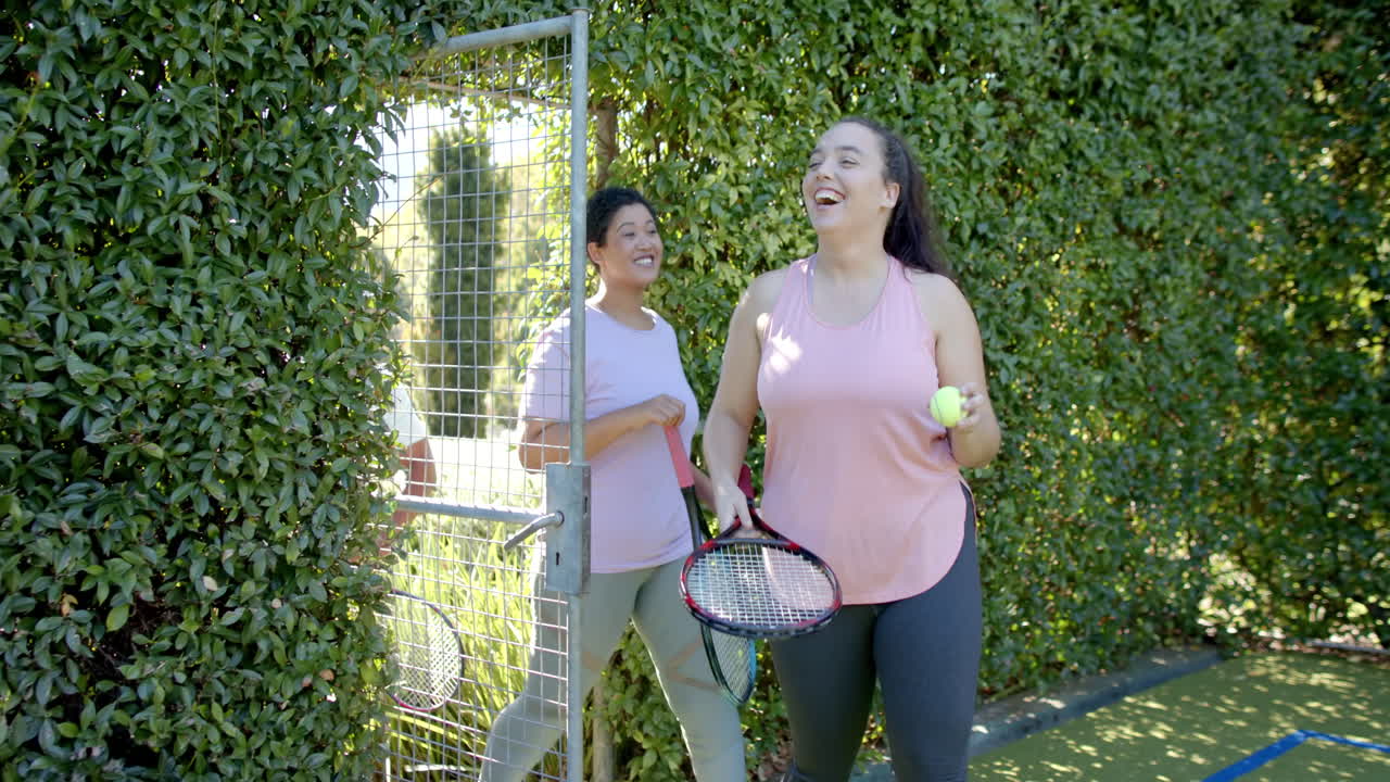 Entering tennis court, Diverse Friends with rackets and ball, smiling and laughing