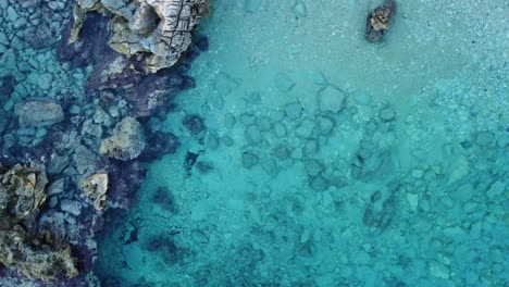 Crystal-clear-turquoise-water-in-secluded-Sardinian-bay,-aerial-top-down,-orbit
