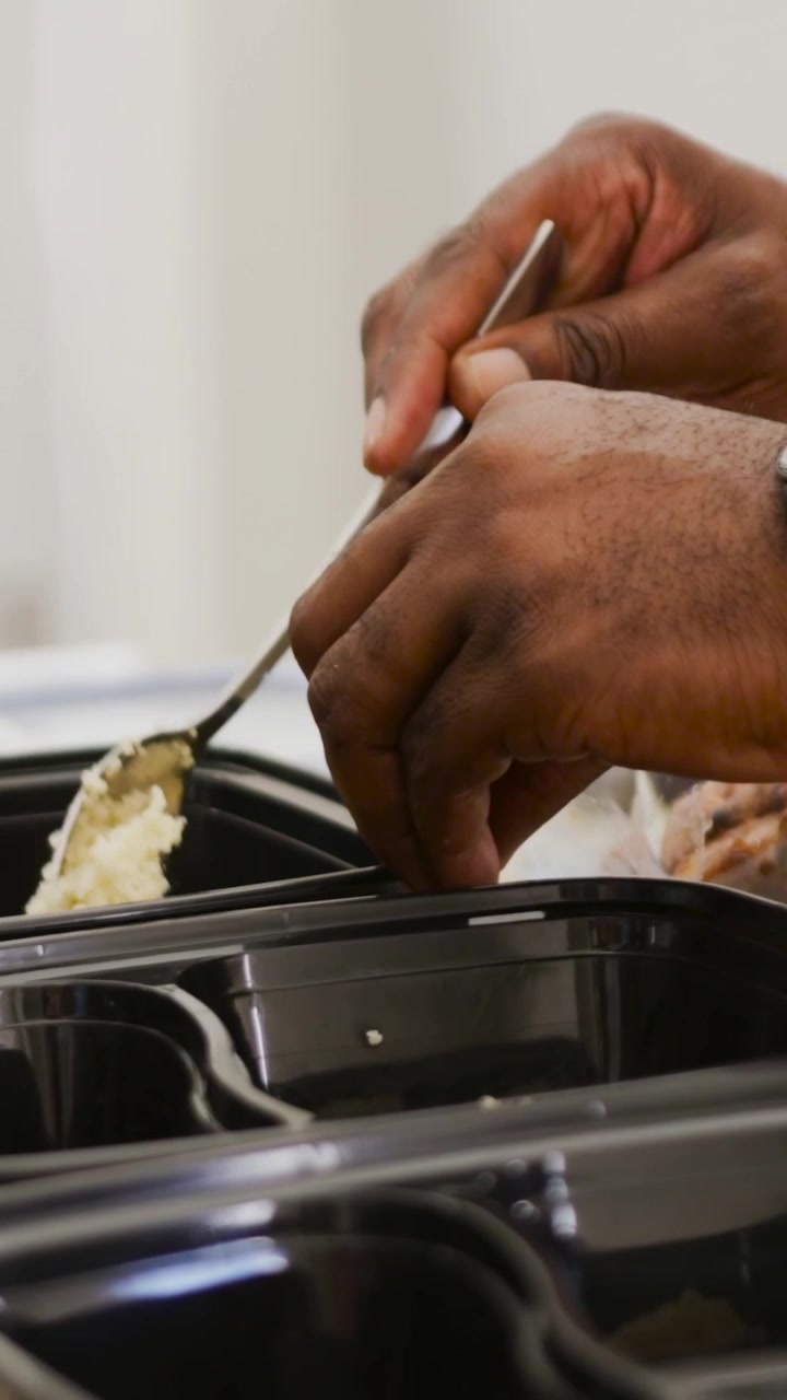 Video verticale: Mani con orologio che sollevano un cucchiaio e riempiono di riso dei vassoi in cucina per la preparazione.