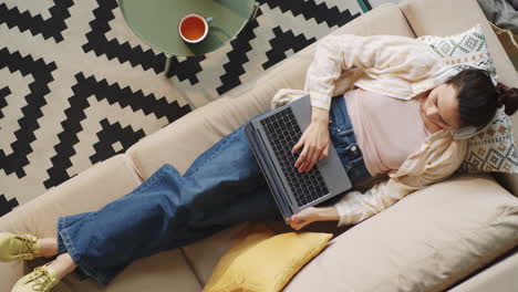 woman in headphones browsing the web laptop at home