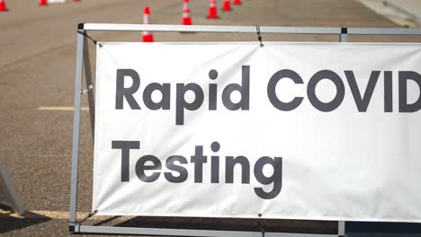 rapid covid-19 testing site sign posted outside on sunny and hot summer or spring day in empty parking lot with orange cones setup