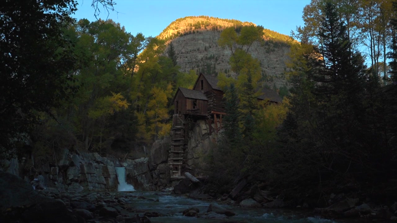 The Crystal Mill, gammel sølvminebygning, klippefremspring, kraftværk, vartegn i Marble Colorado. Efterårsfarver, Crystal River vandfald, eftermiddagssolnedgang, blå himmel landskab, panorerer opad.