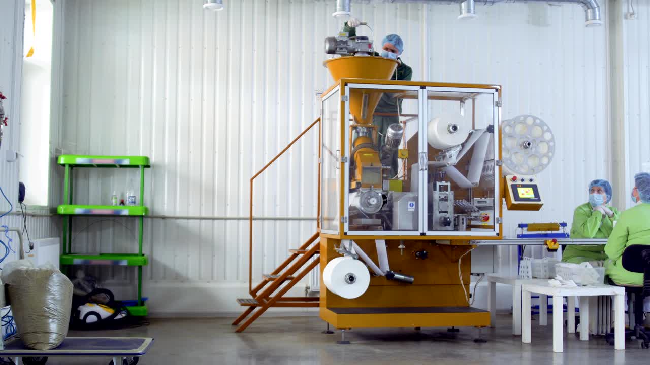 Worker put dry tea inside machine for packaging it into bags