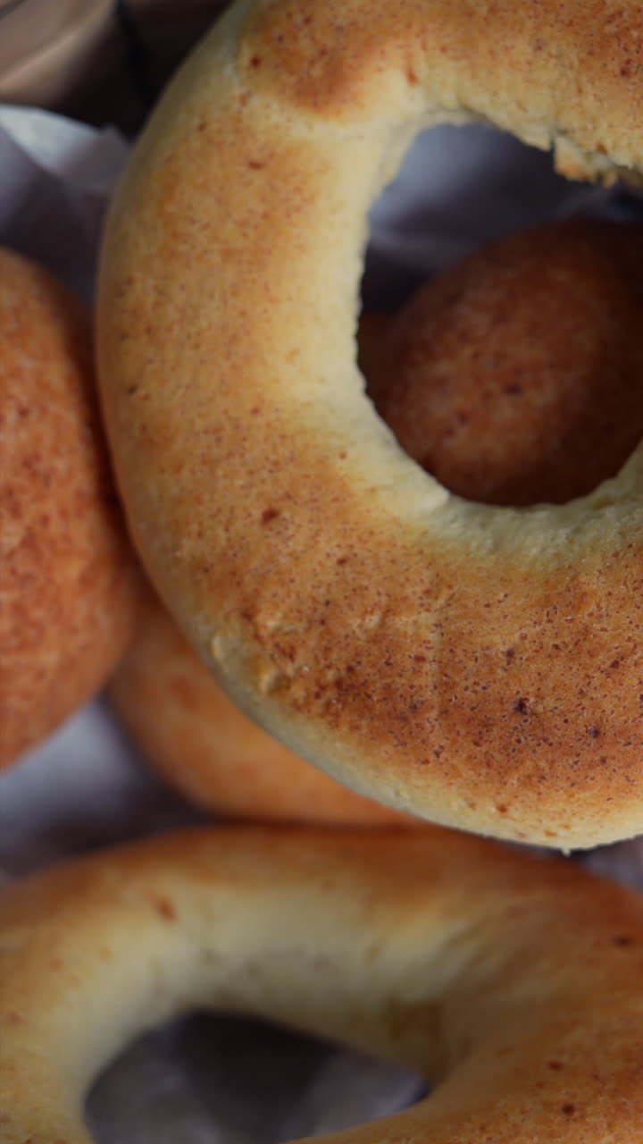 Vertical video close-up of golden almohabanas and pandebonos, showcasing texture and detail in warm lighting. Ideal for mobile and social media content