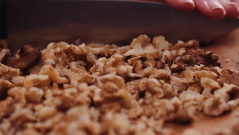 Chopping-Walnuts-With-Kitchen-Knife-On-A-Wooden-Board---close-up