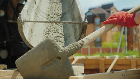 pour concrete from the mixer into the formwork. in the background, blurred new buildings. construction of cottages concept