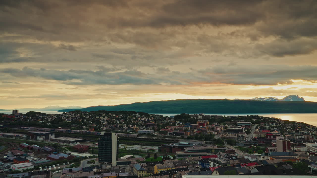 Midnight sunset over the nordic city of Narvik in Norway. View of the majestic fjords, the Norwegian sea and the cloudy, golden sky.
Picturesque arctic landscape.