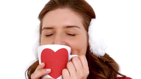 Girl-in-winter-clothes-smiling-at-camera-behind-her-coffee