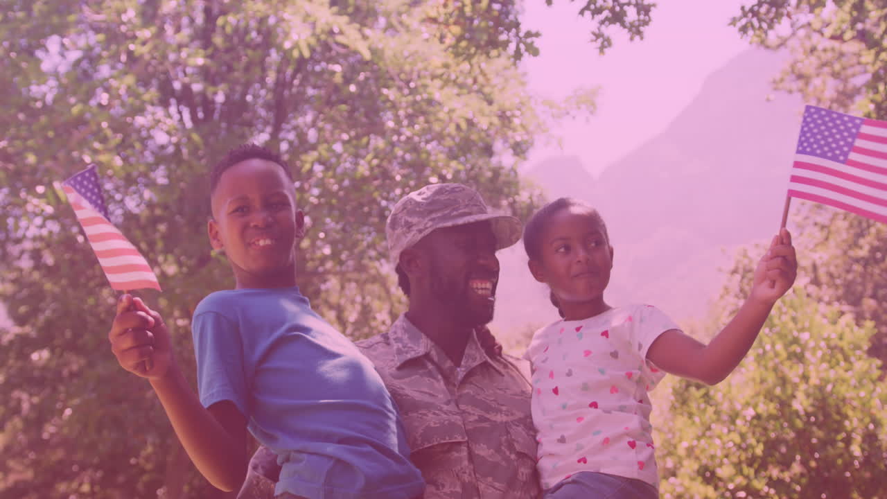 афроамериканский отец в солдатской форме, несущий сына и дочь в саду