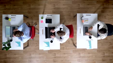 three young businessman are working on laptops, leaving workplace simultaneously, work concept, office concept, communication concept, top shot