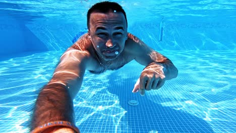 swimming underwater man in pool. man doing underwater selfie shot in pool