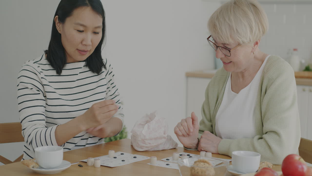 Grandmother and granddaughter playing a board game at home