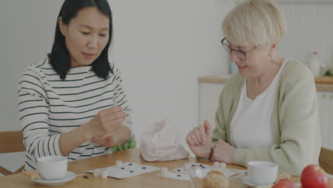 grandmother and granddaughter playing a board game at home