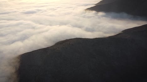 Sunrise-drone-shot-of-mountains-in-between-a-mattress-of-clouds-in-Lima-Peru