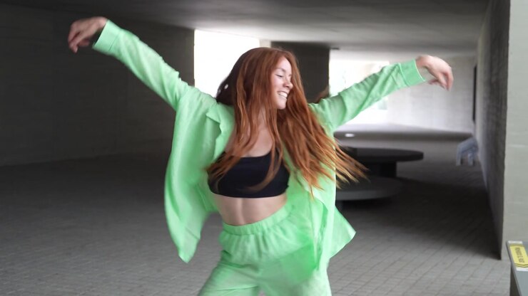 A woman energetically dances in green urban tunnel expressing joy with dynamic choreography