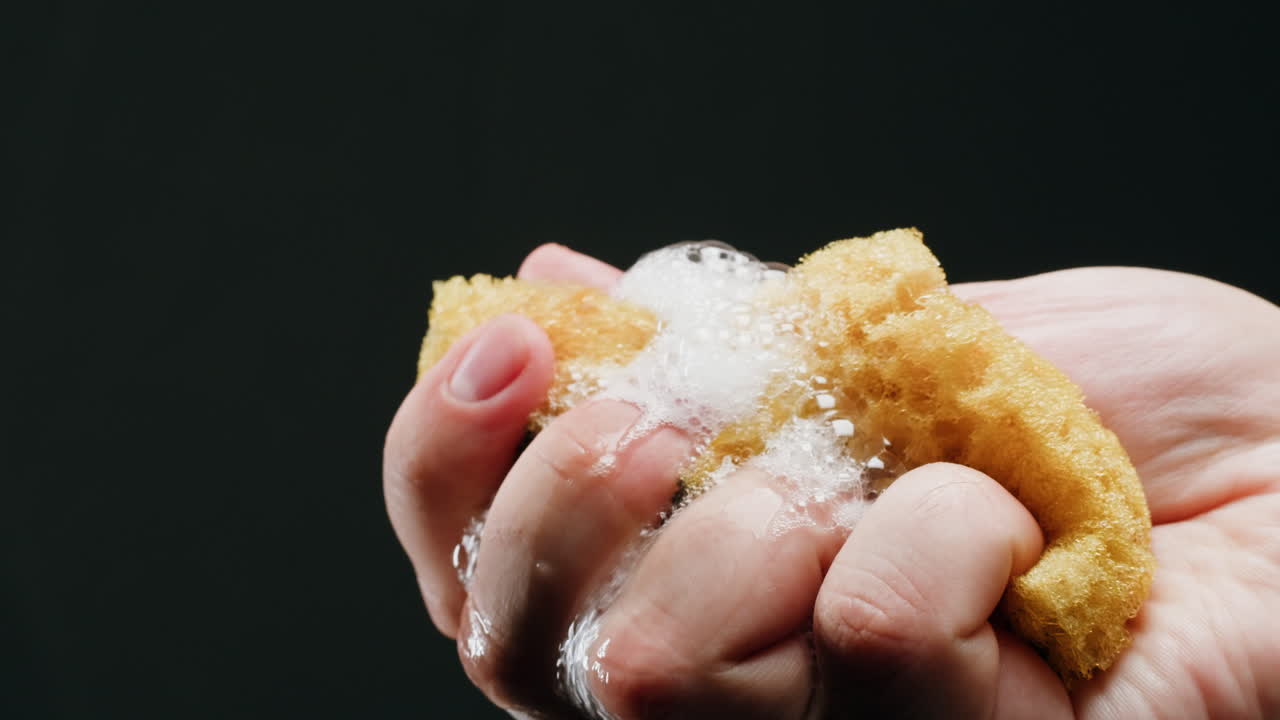 Hand holding a sponge with soap and water