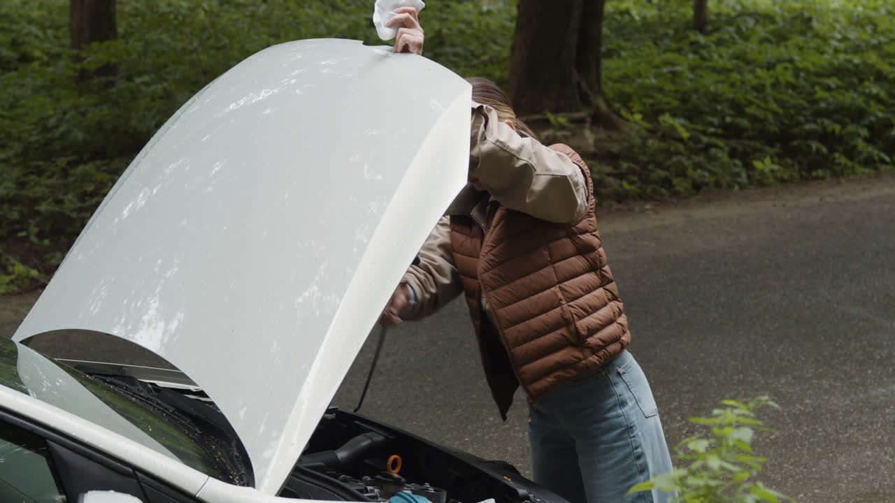 Woman inspecting a car engine outdoors