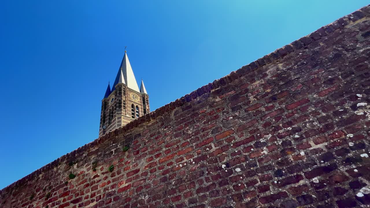 가시와 벽돌 벽과 선명한 파란 빛의 가톨릭 탑