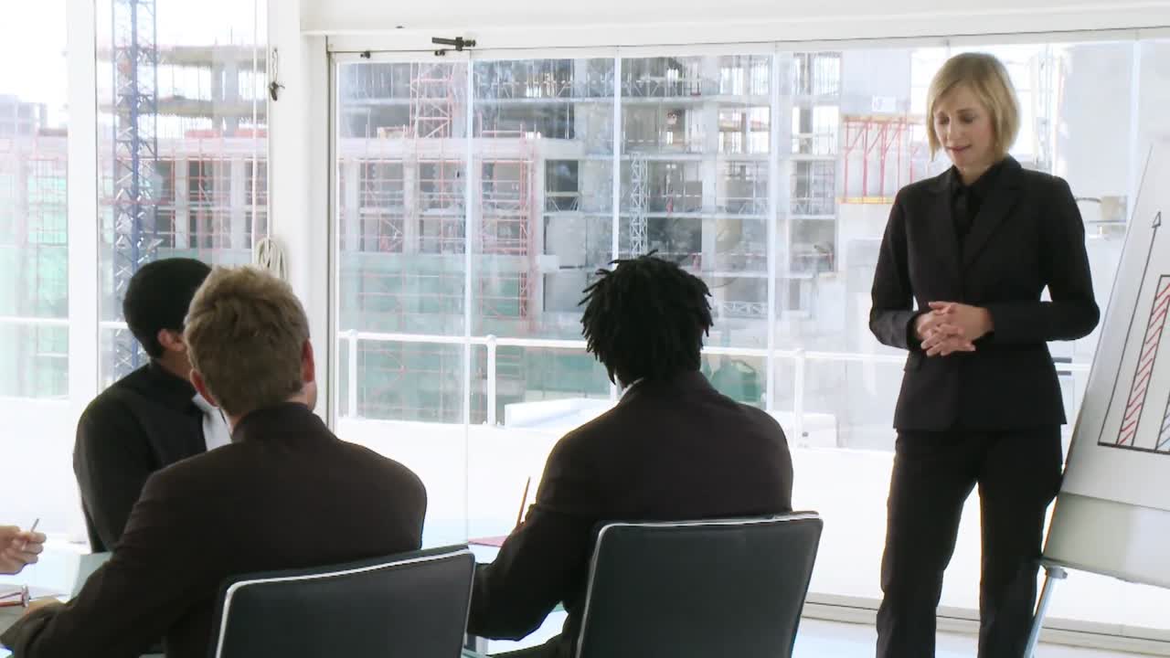 사업가 여성 이 팀 에게 사업 결과 를 설명 하고 있다