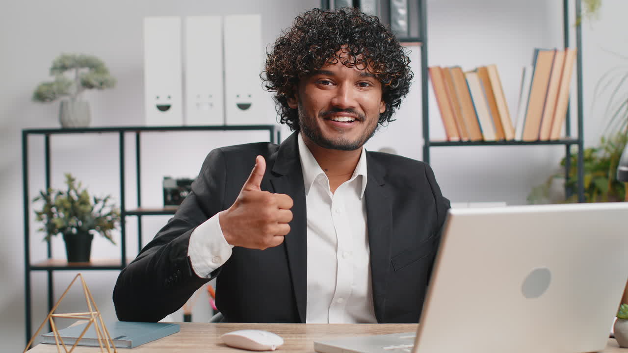 Happy business man looking approvingly at camera showing thumbs up like positive sign good news