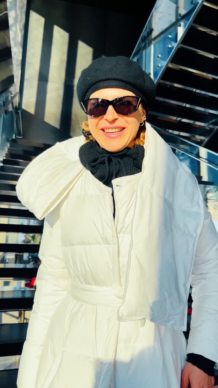 Mujer sonriendo en las escaleras dentro de la estructura Vessel. Retrato cercano de mujer con abrigo blanco y boina negra en las escaleras metálicas dentro de Vessel, Nueva York.