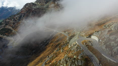 cinematic drone footage of the susten pass in the swiss alps in switzerland , coming out of the clouds