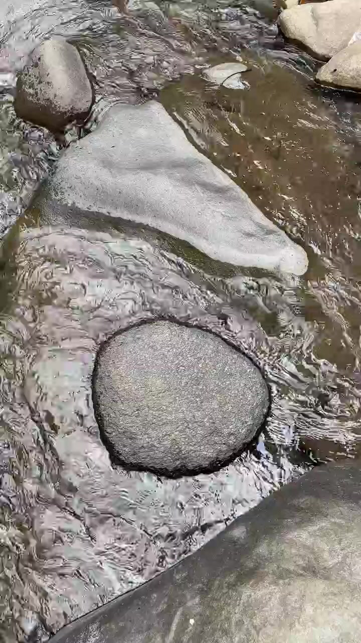 Acqua limpida che scorre su ciottoli di fiume lisci.
