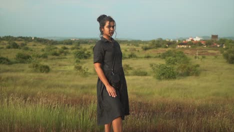 Confident-young-woman-in-pretty-black-dress-making-eye-contact-with-the-camera,-posing