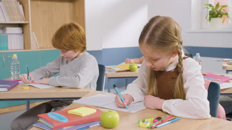 female student sitting at desk in english classroom writting in her notebook