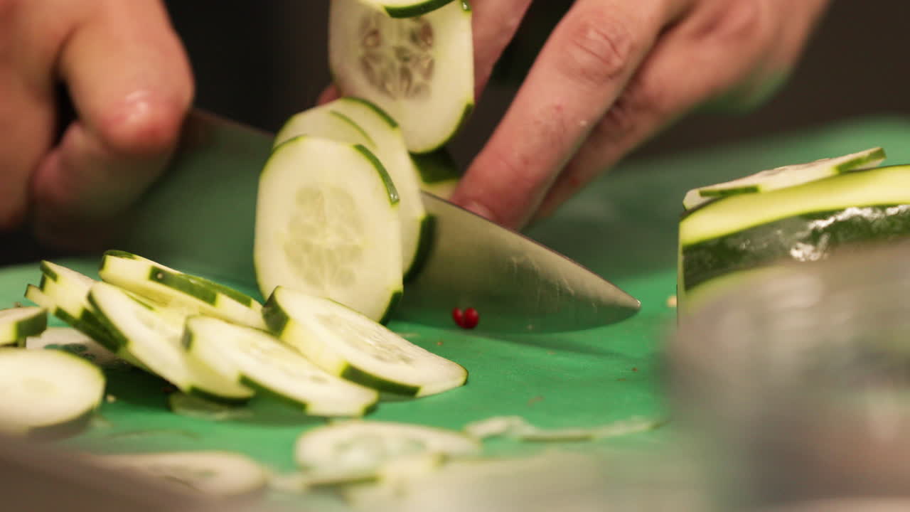 Chef's Hand Chopping Cucumber Using A Sharp Knife In The Kitchen Of A Restaurant. - close up shot