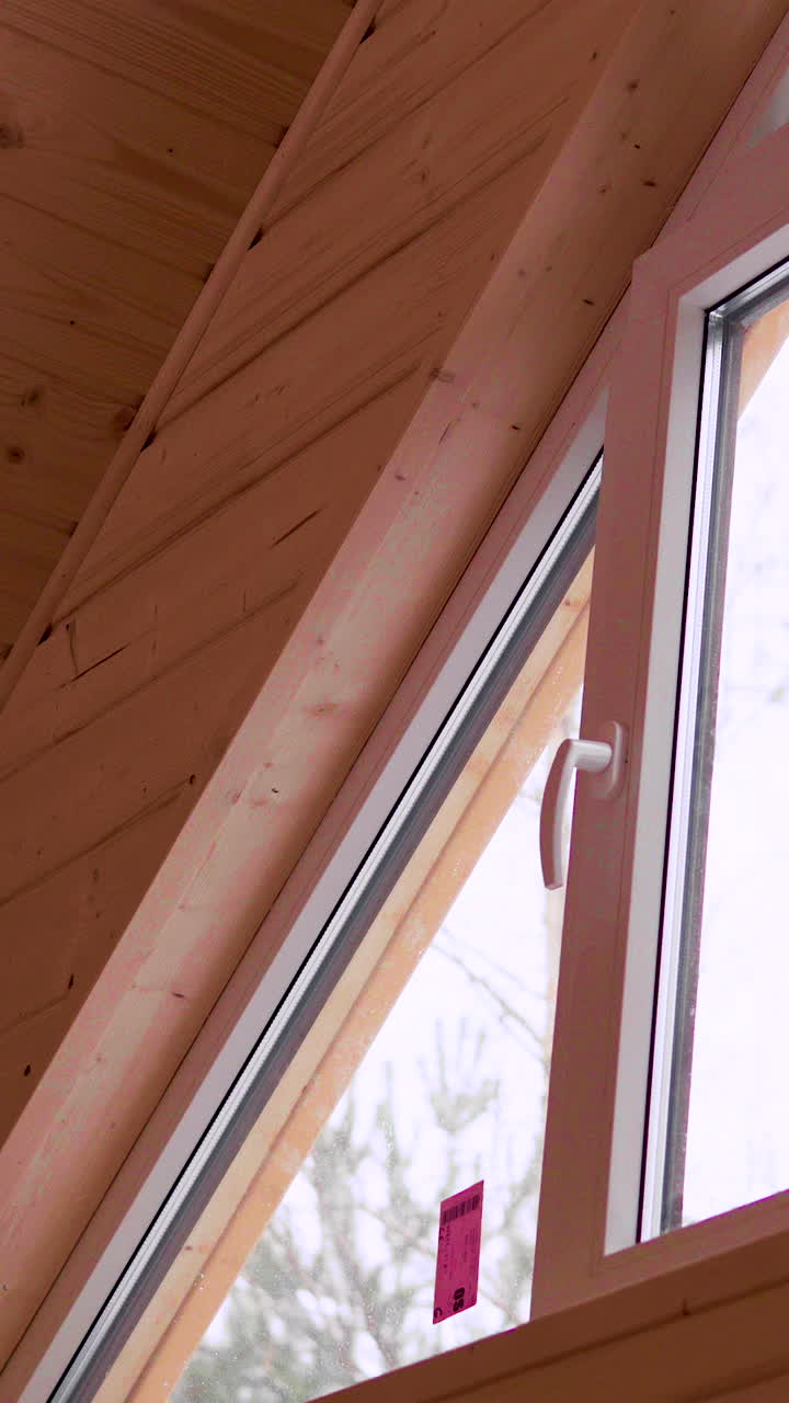 A closeup view of a wooden ceiling a slanted window. Ideal for architectural presentations, interior design showcases, and home renovation projects. Smooth panning camera movement