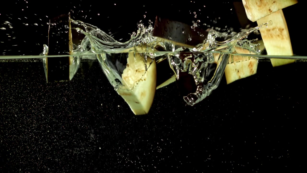 Chopped Eggplant Pieces Falling into Water with Splashes in Slow Motion