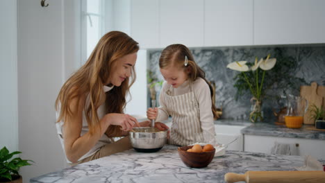 mother daughter creating dough home interior. laughing family preparing pastry