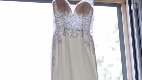 wedding dress hanging near a window, slow motion shot