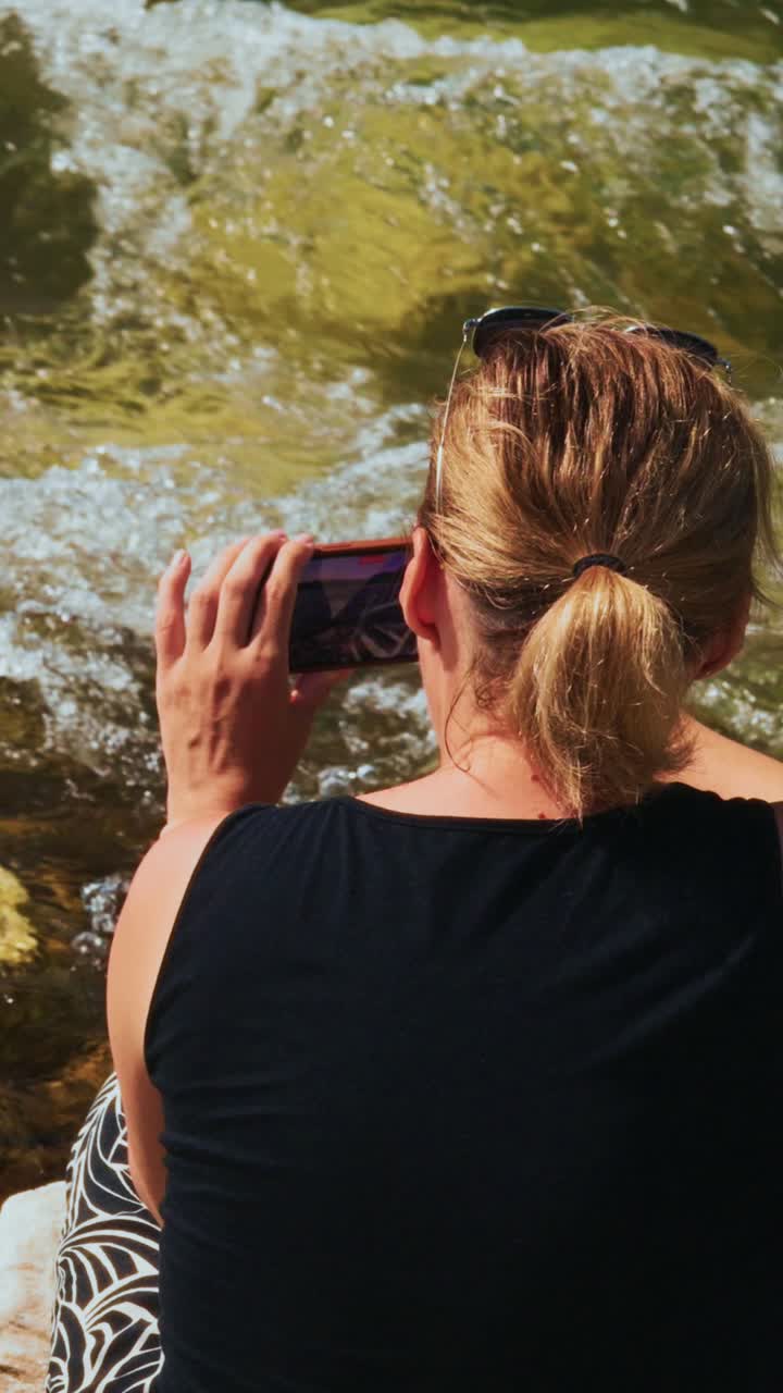 Woman Recording Flowing River Water with Smartphone