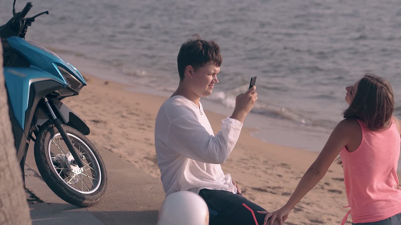 검은색 쇼트를 입은 남자가 앉아서 아름다운 여자의 사진을 찍습니다.