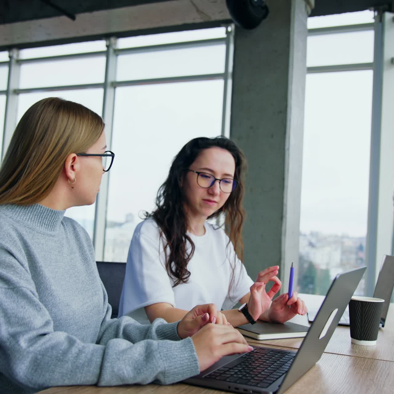 Una giornata tipo in un ufficio moderno. Donne sedute alla scrivania che parlano e un uomo che parla al telefono mentre cammina vicino alla finestra.