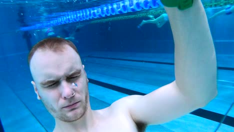 Man-holding-breath,-submerged-underwater-in-public-indoor-swimming-pool