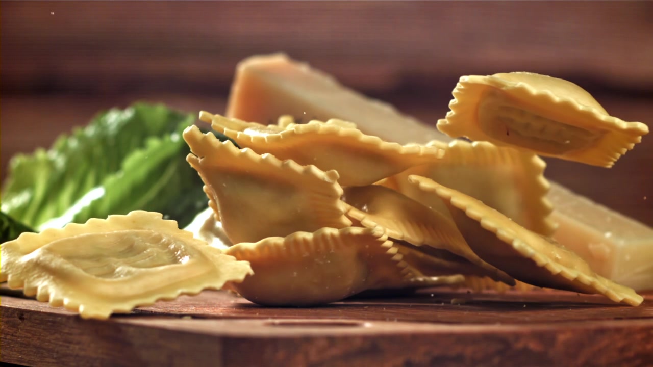 Rallentatore di ravioli freschi che cadono su un tagliere di legno rustico
