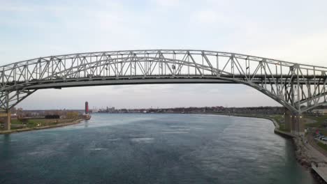 Blue-Water-Bridge-connecting-Port-Huron,-Michigan-USA-and-Sarnia,-Ontario-Canada-in-the-evening-drone-video-moving-forward