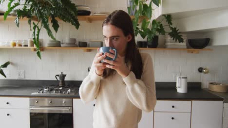 Caucasian-non-binary-transgender-woman-drinking-coffee-in-kitchen