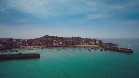 cinemagraph - seamless video loop of the beach and harbor promenade of the famous old town st. ives in cornwall in southern england, uk with fishing boats moving in the clear blue seaside water